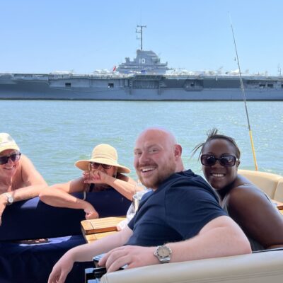Friends on a yacht charter in the Charleston SC harbor viewing the USS Yorktown